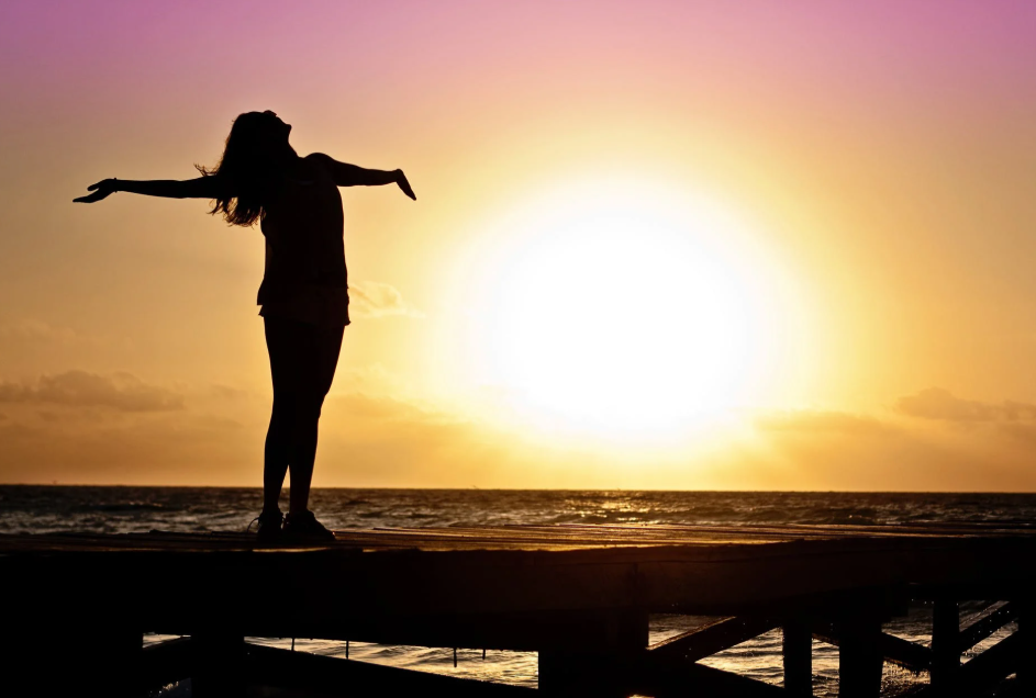 silhoutte of a woman standing with sunrise on the background